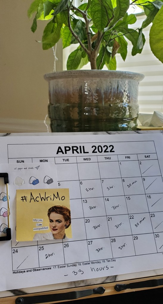 Photo of printed April Calendar with a sticky note that says "#AcWriMo" 